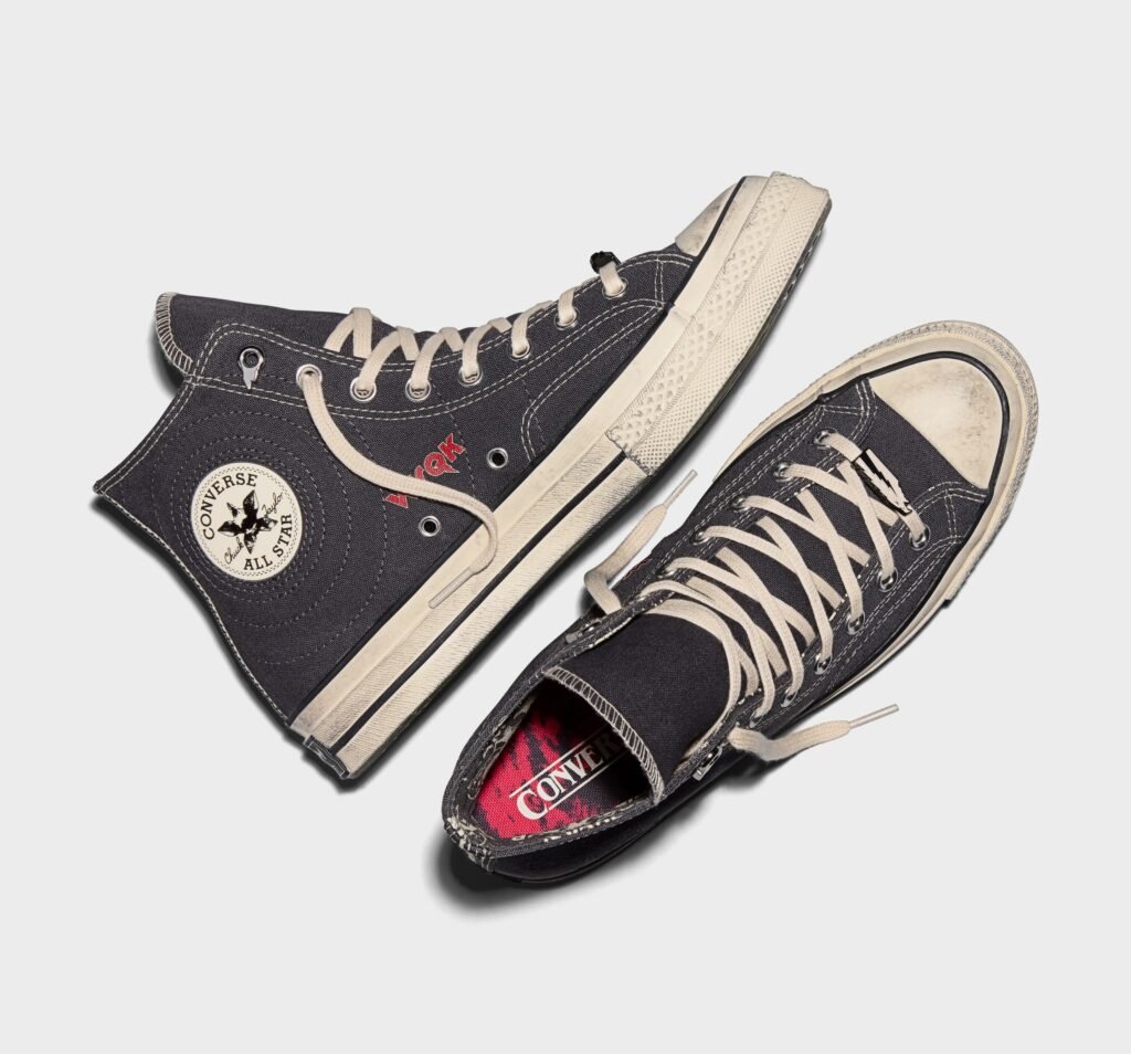 A pair of black Converse Chuck Taylor All-Star high-top sneakers with white laces and a white sole; the shoes feature the Converse logo on the side and the word 'New York' printed on them.