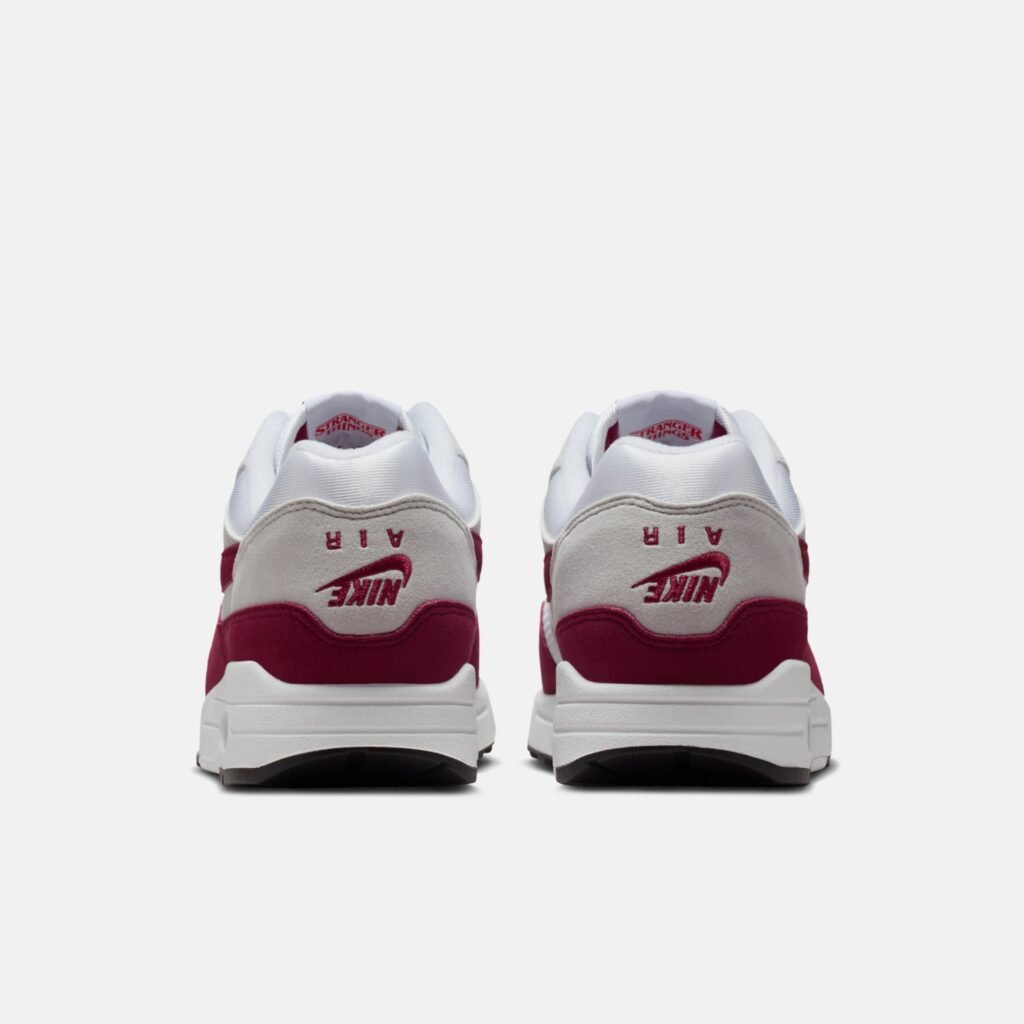 Rear view of a pair of Nike Air sneakers in red and white, featuring the Nike logo and 'AIR' text on the heels.