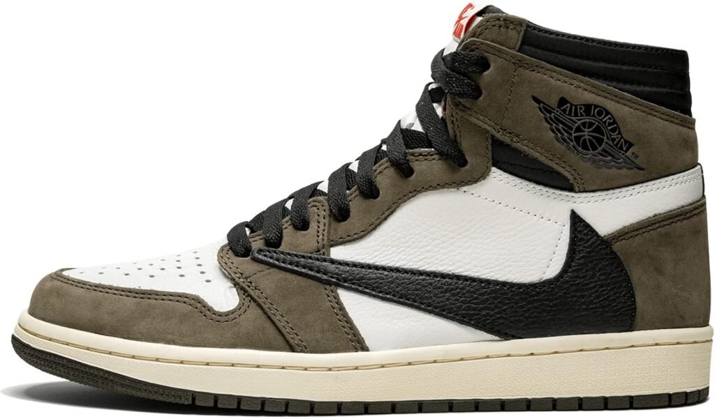 A high-top Travis Scott sneaker featuring a brown suede overlay, black laces, and a backward black swoosh on a white leather base, with branding on the ankle area.