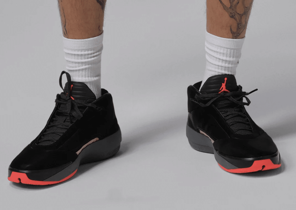 Person wearing black Air Jordan 40 'Infrared' shoes with a red logo and red accents, paired with white socks.