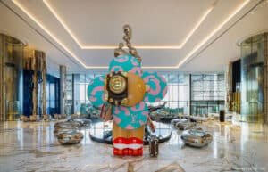 Large, colorful flower-like sculpture with abstract designs displayed in a modern, spacious lobby with sleek decor.