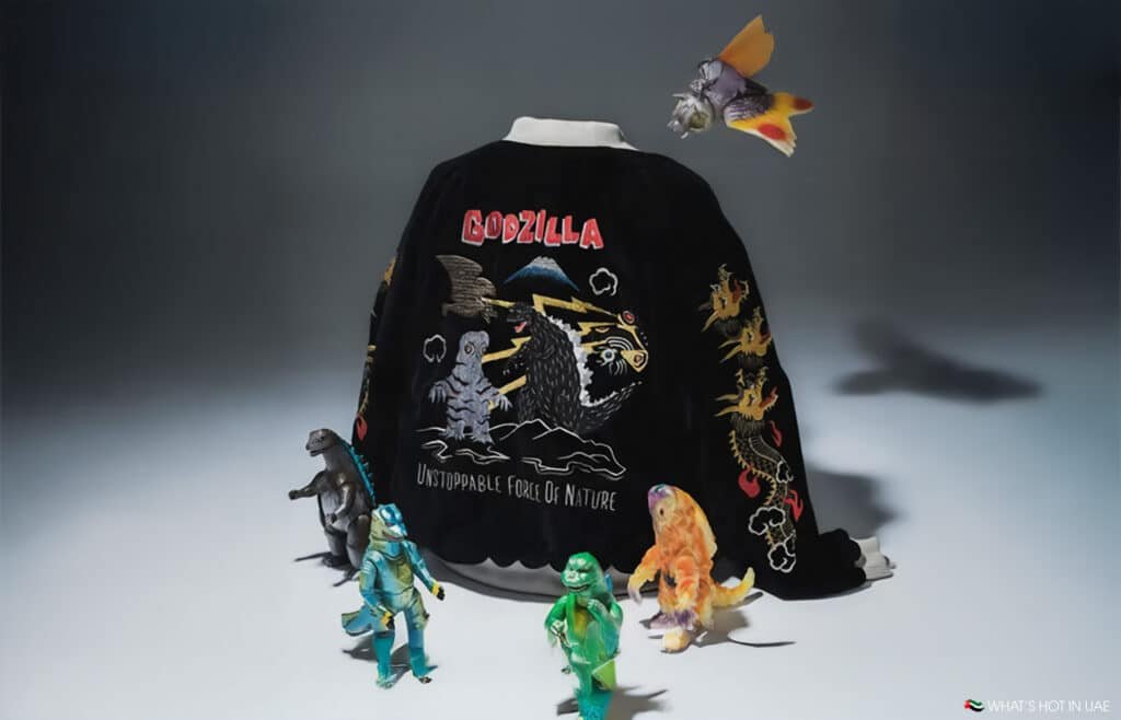 A Godzilla-themed jacket with colorful embroidery of Godzilla, a dragon, and other creatures, alongside several small toy monsters.