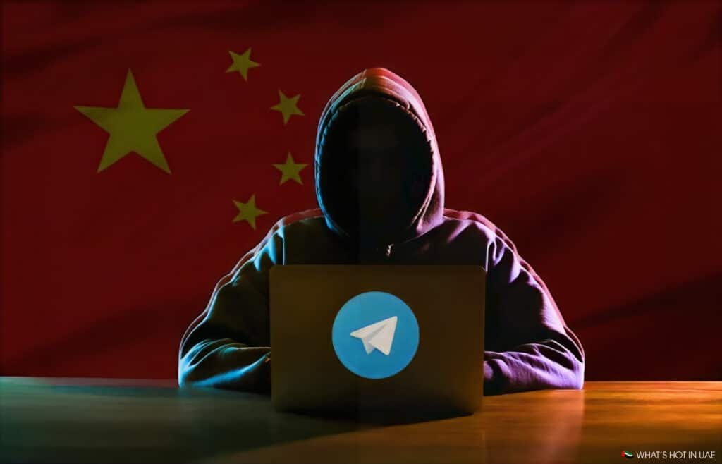 A person in a hoodie uses a laptop with a Telegram logo in front of a Chinese flag background.