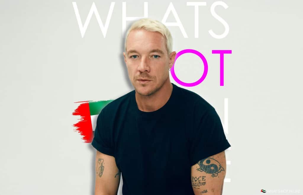 A person with short blond hair and tattoos on their arms, wearing a black shirt. The background includes the text "WHAT'S HOT" with a graphic resembling the flag of the United Arab Emirates and the words "WHAT'S HOT IN UAE" in the lower corner.
