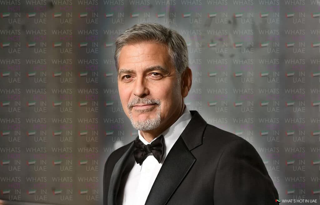 A man in a tuxedo stands in front of a backdrop featuring the text 'WHAT'S HOT IN UAE' repeatedly.