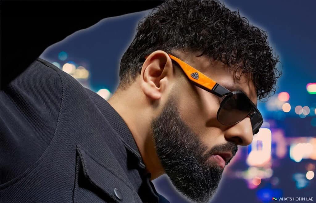Badshah wearing MAYBACH Eyewear sunglasses and a dark jacket against a blurred cityscape background at night.