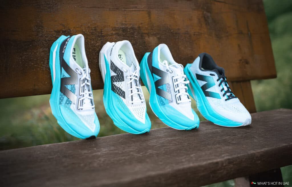 Four pairs of white and turquoise sneakers with distinct black patterns on a wooden bench outdoors.
