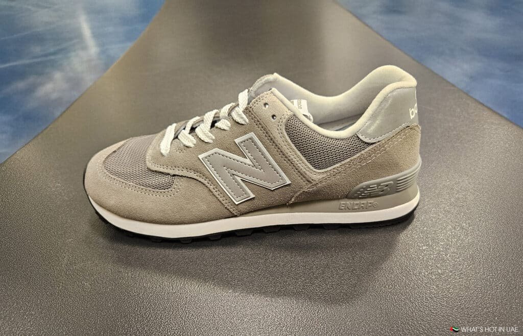 A gray and beige sneaker with a prominent "N" logo on the side, featuring a cushioned sole and white laces.