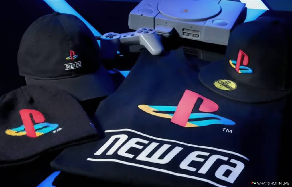 Clothing and accessories displaying PlayStation and New Era logos, with a classic game console and controller in the background.
