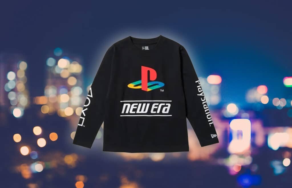 Black long-sleeve shirt with a colorful PlayStation logo and "new era" text, set against a blurred city lights background.