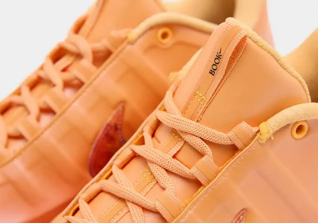 Close-up of orange sneakers with orange laces and a visible "BooK" logo on the tongue.