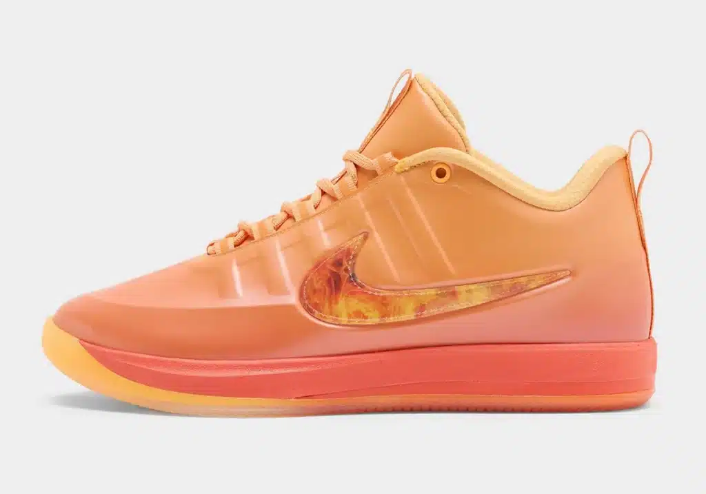 Orange low-top Nike Book 2 Phoenix sneaker with a translucent orange and red swoosh, featuring a gradient sole from tan to red.