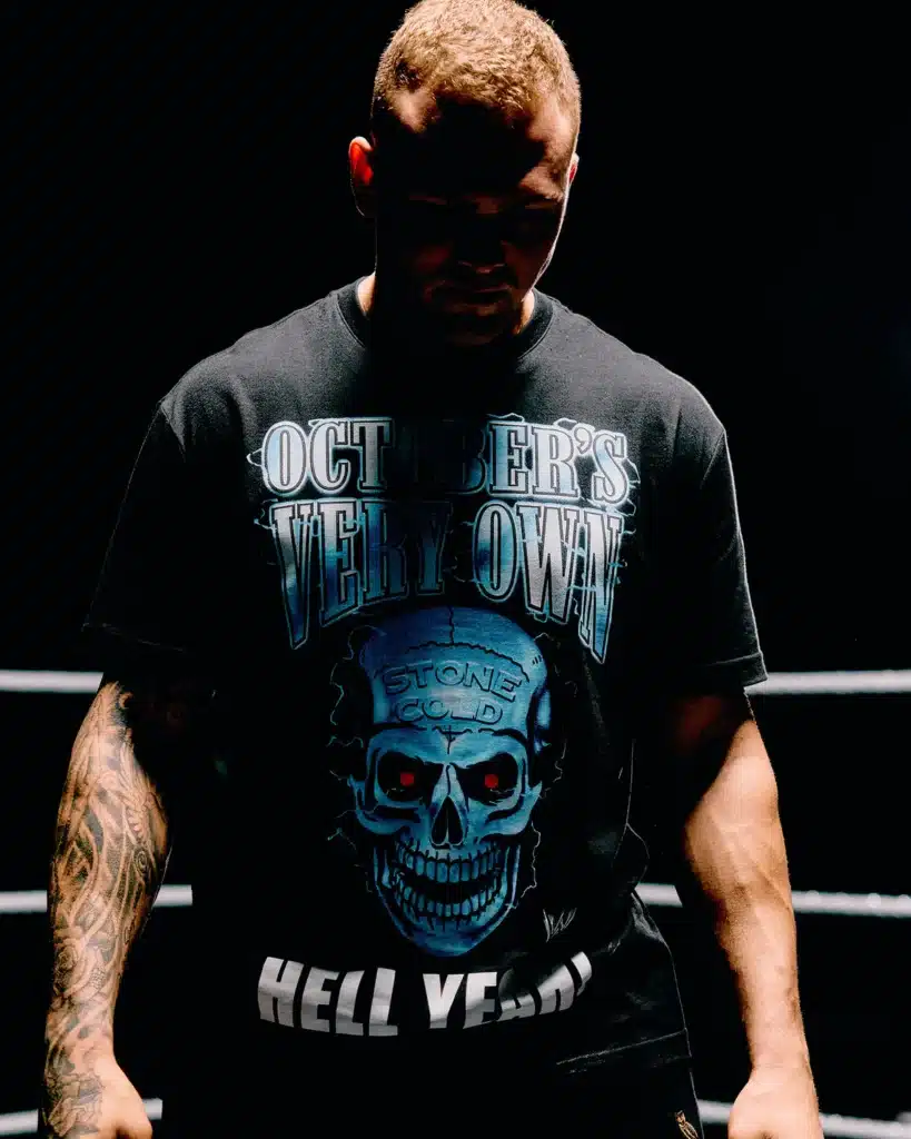 A person stands in shadow, wearing a black t-shirt with a skull and the words "October's Very Own" and "Hell Yeah!"