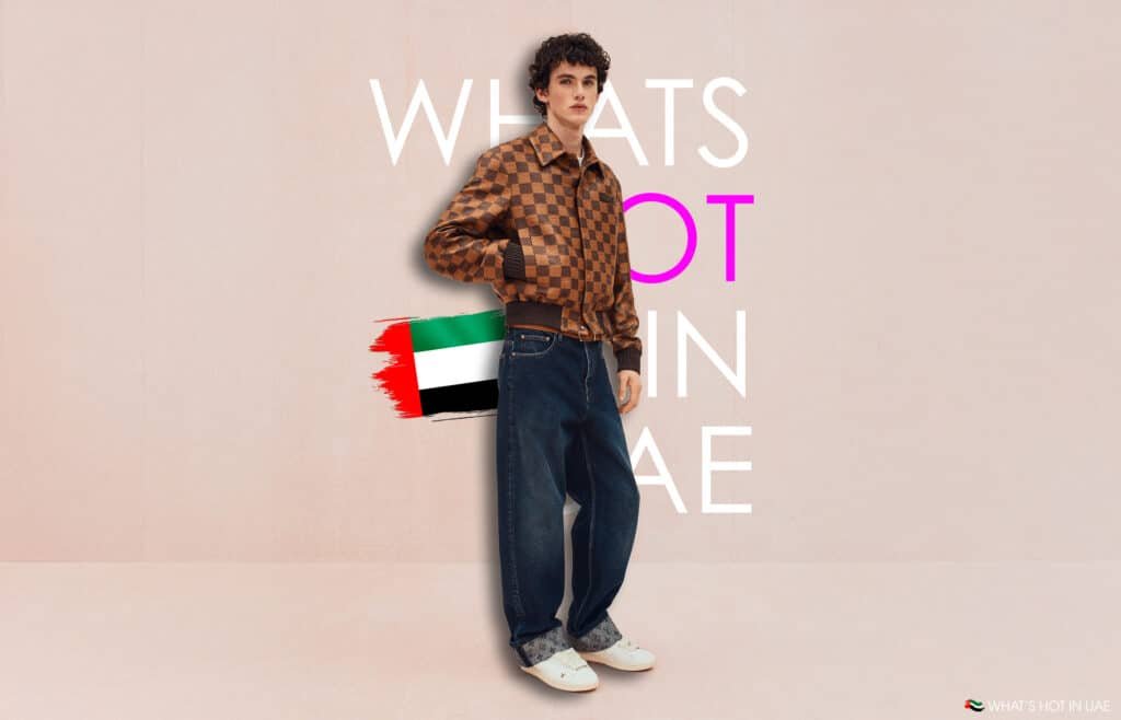 A person wearing a Louis Vuitton Pre-Fall 2026 checkered brown jacket and dark blue jeans stands on a pink background with the text "What's Hot in UAE" and a small UAE flag graphic.