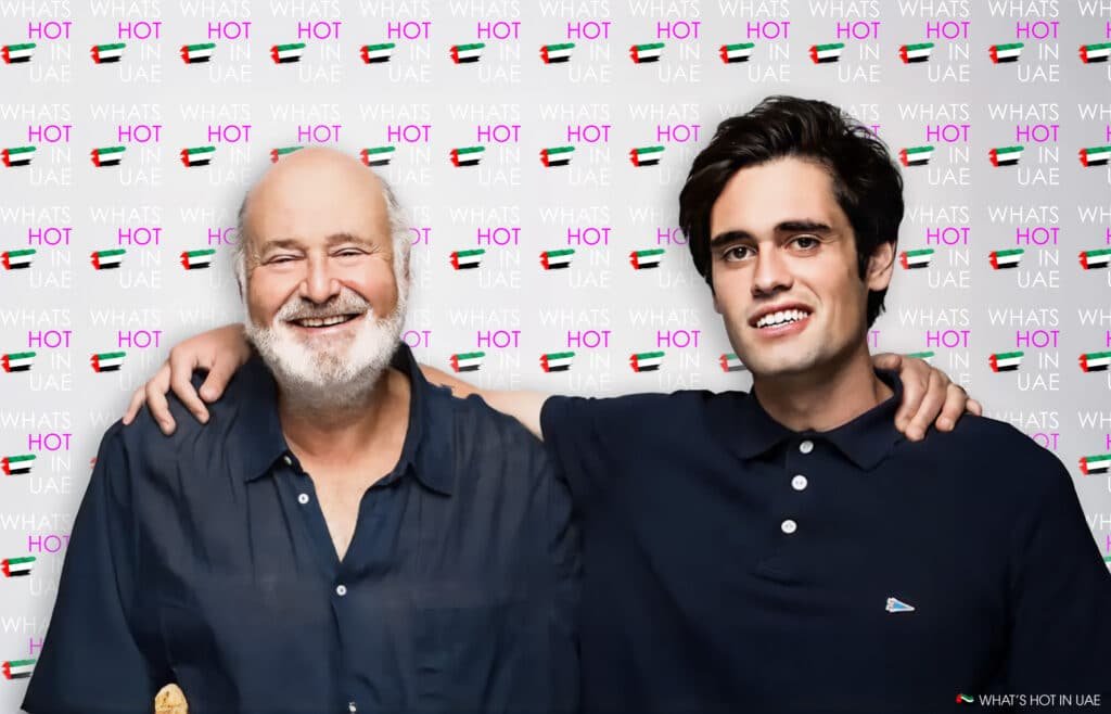 Two smiling men, Rob Reiner with a bald head and beard, and Nick Reiner with dark hair, standing arm-in-arm against a backdrop that reads 'WHAT'S HOT IN UAE' with images of the UAE flag.