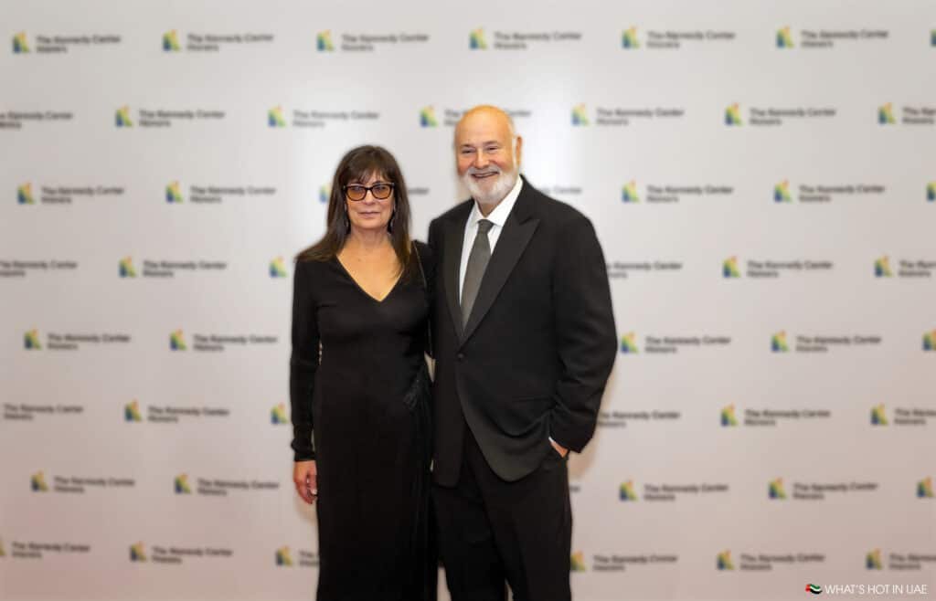A man and a woman dressed formally, posing together on a red carpet with a backdrop labeled 'The Kennedy Center Honors.'