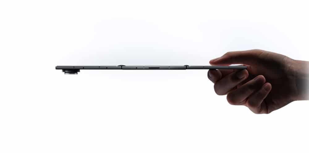 A side view of a slim Samsung Galaxy Z TriFold held by a hand, showing its thin profile and protruding camera lens.