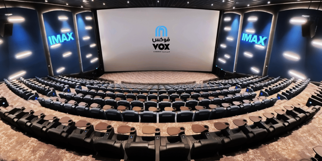 An empty IMAX Yas Mall cinema theater with tiered seating and large screens displaying the IMAX and VOX logos.