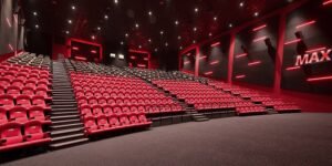 Empty movie theater with red seats, sloped aisles, and walls featuring red LED lighting.