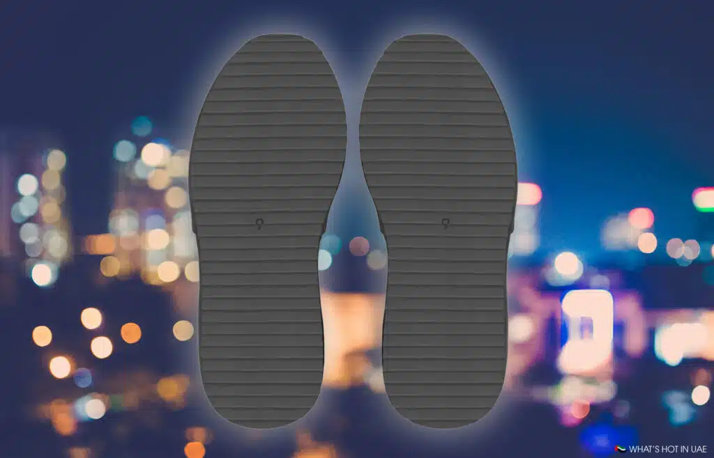 Textured black YEEZY BL-01 shoe soles with a cityscape of blurred lights in the background.