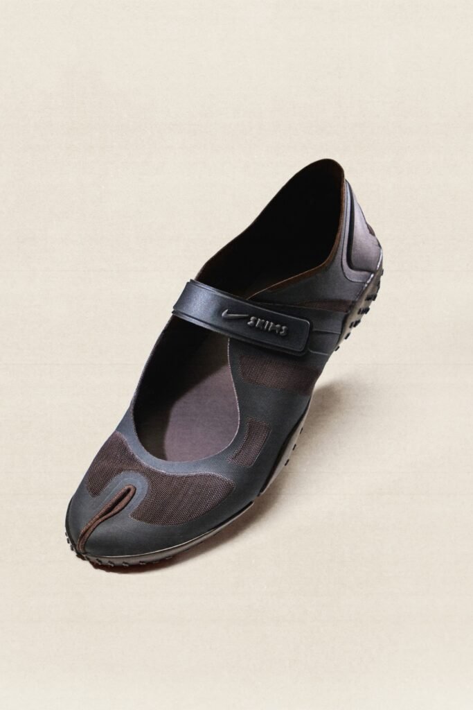 A dark NikeSKIMS Rift Mesh shoe with a split toe design, mesh upper, and strap closure on a light background.