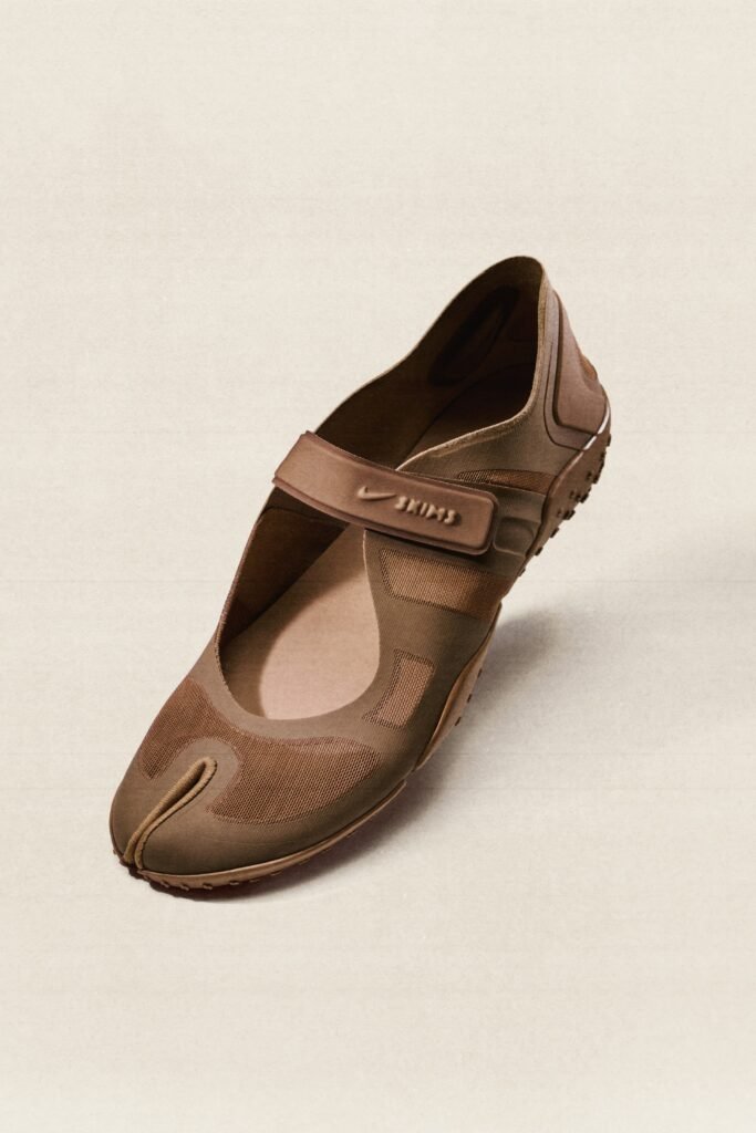 A brown Mary Jane-style shoe with a Velcro strap and a unique split toe design.