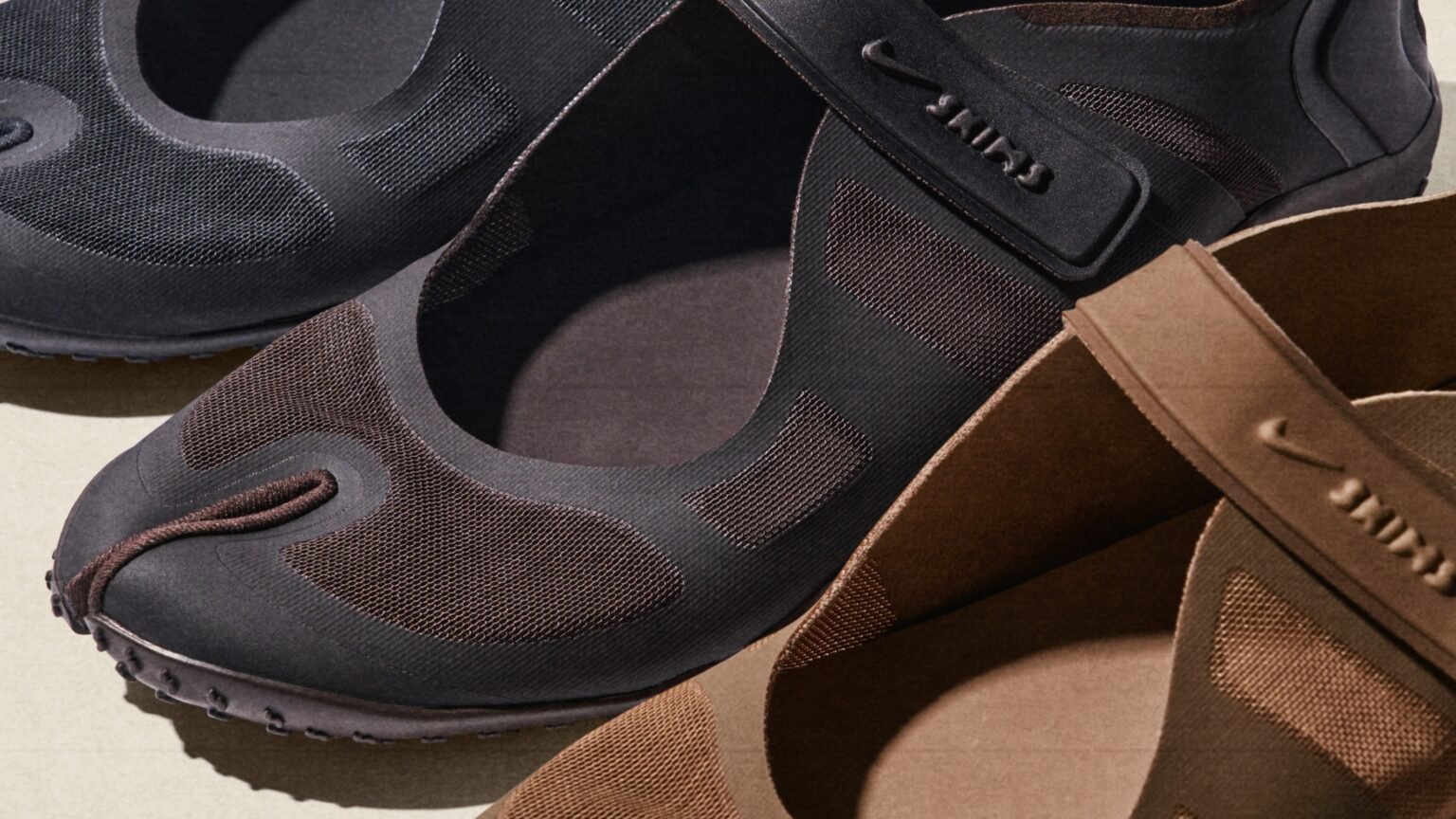 Three pairs of dark-colored slip-on shoes with rounded toes and flexible mesh material on a light background.
