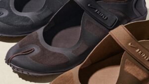 Three pairs of dark-colored slip-on shoes with rounded toes and flexible mesh material on a light background.