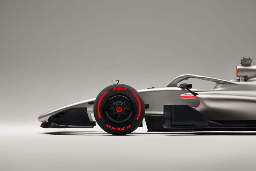 A sleek silver Audi Revolut F1 car from the side, featuring a prominent Pirelli tire with a red accent.