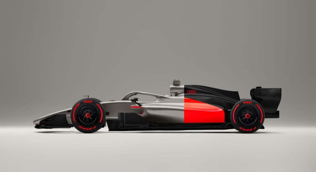 A sleek Audi Revolut F1 race car with a silver and black body, featuring red accents and visible aerodynamic design elements.