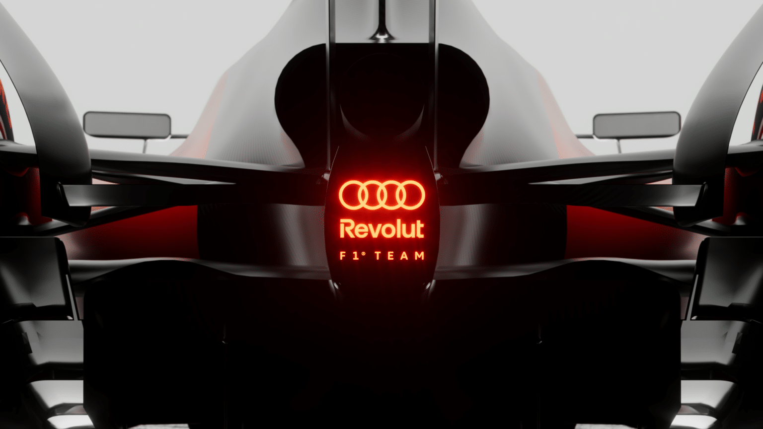 Rear view of a sleek Formula 1 car displaying the logos "Revolut" and "F1 Team" with an illuminated red logo above.