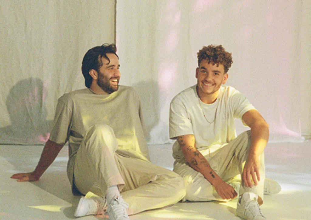 ANOTR sitting on the floor, smiling at each other, in a softly lit studio with neutral-colored drapery in the background. ANOTR Live at Pacha ICONS