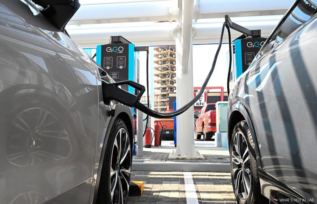 Two electric cars charging at a Adnoc E11 EV station with E.GO chargers, set under a canopy structure.