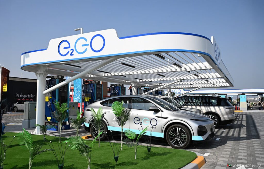 Electric vehicles charging at a modern E2GO charging station with a sleek design and decorative plants outside.