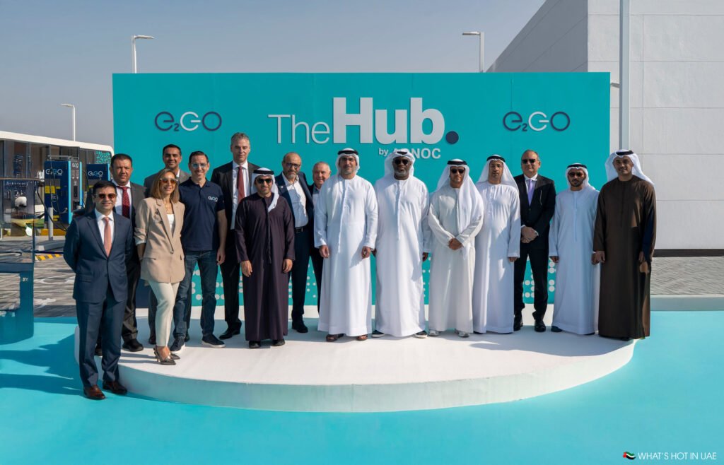 A group of people in formal attire pose in front of a sign that reads "The Hub" with e.GO logos.