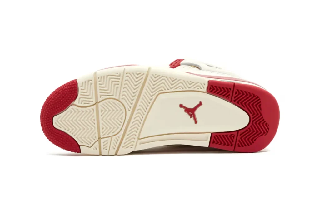 The sole of a sneaker with red and white sections, featuring a red logo in the center.
