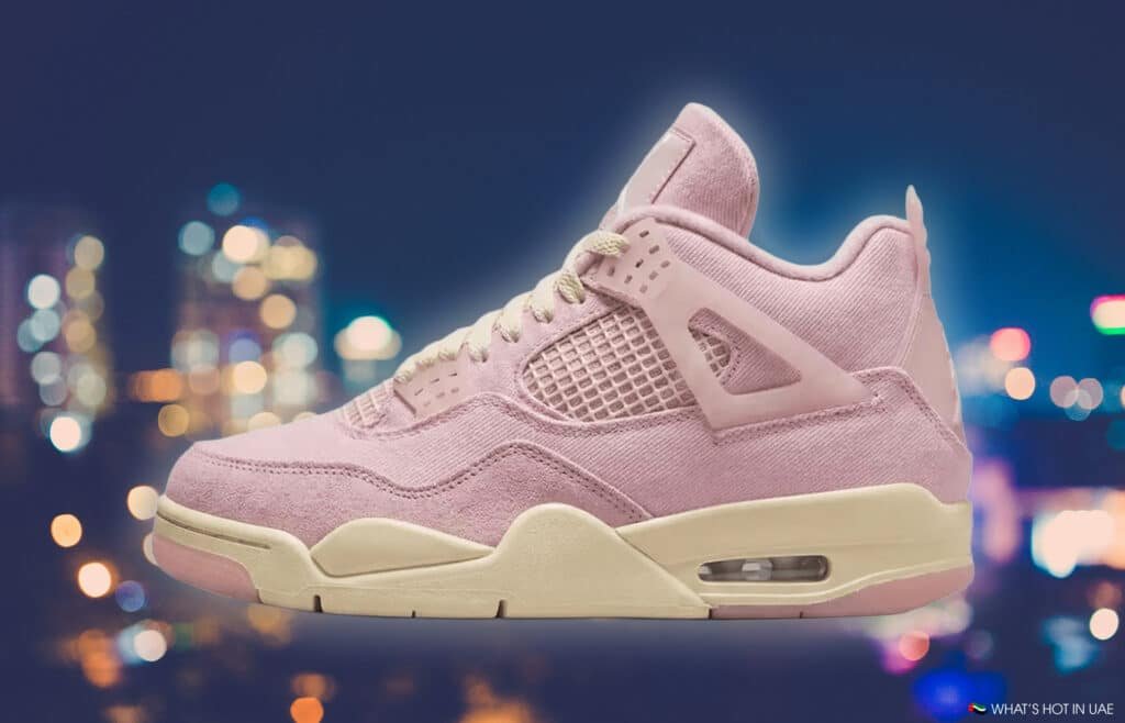Pink sneaker with mesh panels and beige sole, set against a blurred city night background.