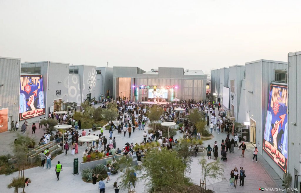 Crowds walking through Alserkal Avenue during Al Quoz Arts Fest, with pop-up vendors, food trucks, and warehouse galleries lining the street.