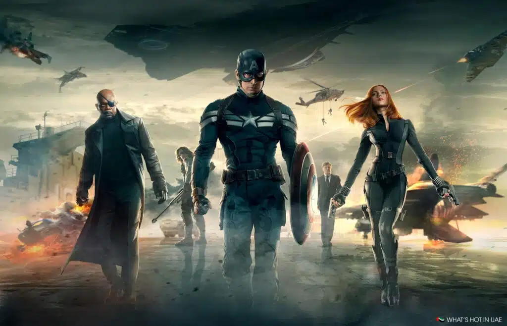 A group of superheroes in action poses, featuring a central figure with a shield, aircraft overhead, and an urban backdrop.