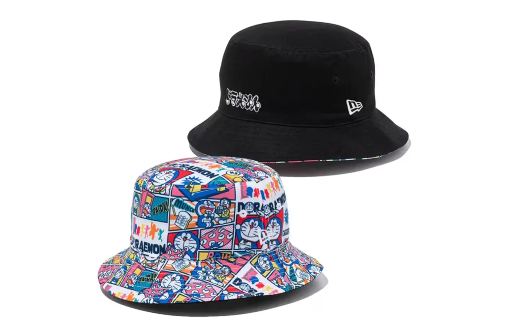 Two Doraemon x New Era bucket hats: one black with a white geometric design and the other featuring a colorful cartoon pattern.