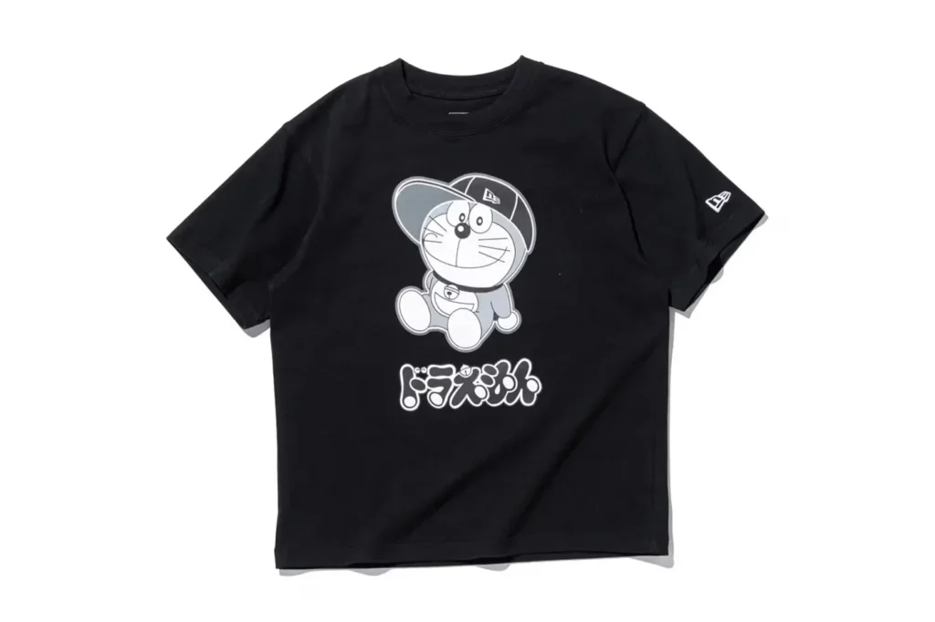 Black Doraemon x New Era T-shirt featuring an illustration of a cartoon character wearing a cap and text in a stylized font underneath.