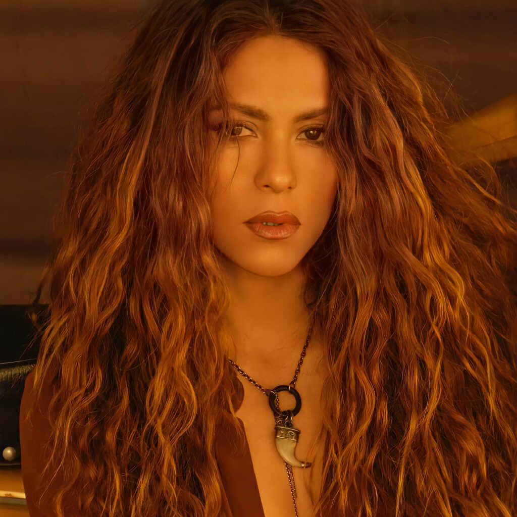 Global Superstar Shakira OFFLIMITS Music Festival with long, wavy auburn hair, wearing a necklace and a brown top, looking directly at the camera.