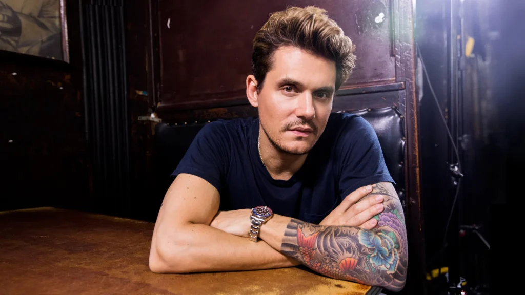 John Mayer with his arms folded on a table in preparation for the John Mayer Saadiyat Nights Concert.