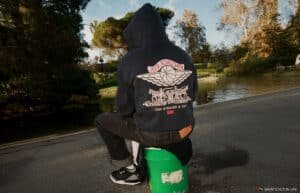 Person sitting by a pond wearing a black hoodie with an Air Jordan and Levi Strauss & Co. design on the back.