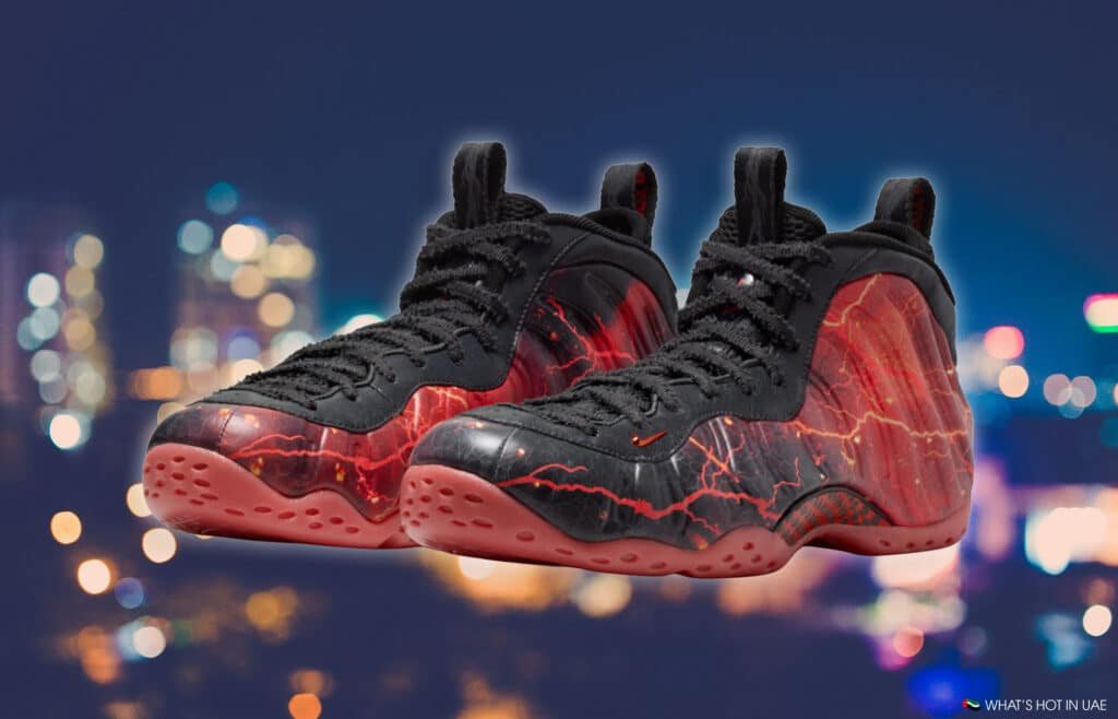 Black and red Stranger Things Air Foamposite sneakers with a lava-like pattern, set against a blurred cityscape background.