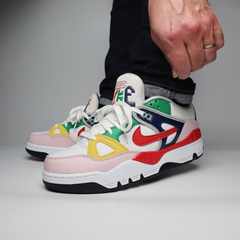 A person wearing colourful Nike x Nigo Air Force 3 sneakers with a vibrant, multi-colored design and a prominent red swoosh logo.