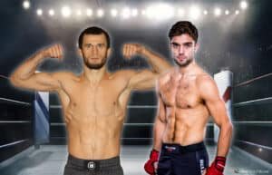Two men pose in a boxing ring, both shirtless and showing muscular physiques, with an audience and bright stadium lights in the background.