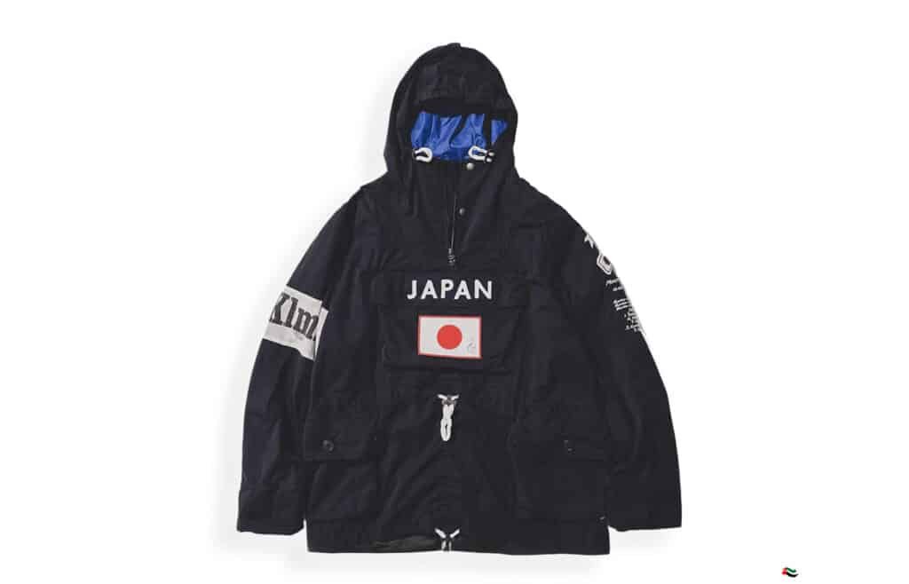 A black hooded jacket with "JAPAN" and a Japanese flag patch on the front pocket, featuring additional white designs on the sleeves.