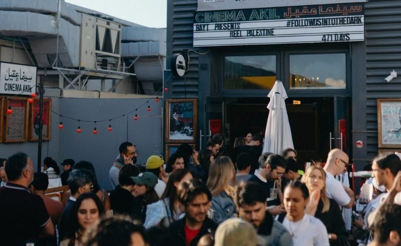 Crowd gathered outside Cinema Akil in Dubai during a Reel Palestine Film Festival screening, with attendees socialising near the venue entrance.