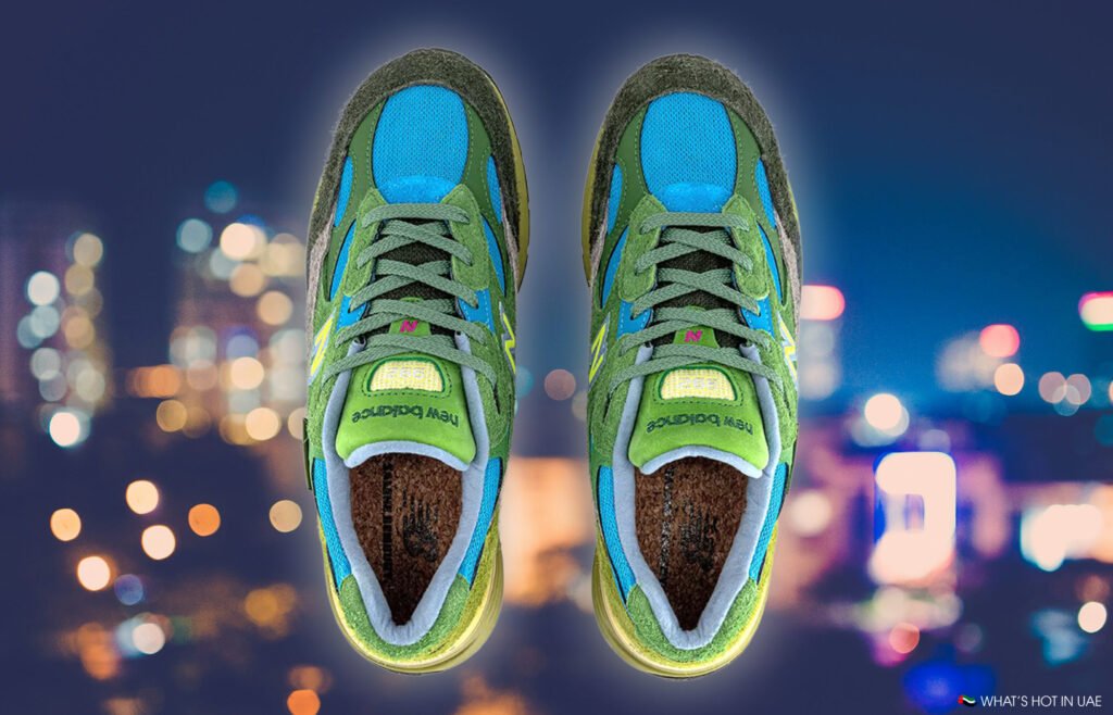 Green and blue Salehe Bembury x New Balance 992 sneakers with New Balance branding, set against a cityscape with blurred lights.